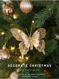 Détail d'un papillon de Noël doré scintillant avec paillettes et strass sur un sapin