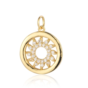 Macro shot of gold sun pendant with cubic zirconia stones on white reflective surface