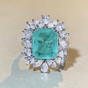 Macro shot of an emerald-cut green gemstone ring with pear-shaped zircon halo setting