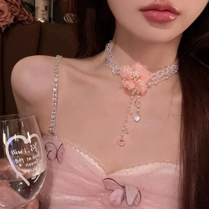 Close-up of a pink fabric flower choker featuring delicate beads and long tassel pendants