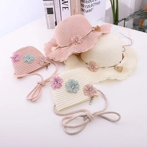Detail of hand-woven straw hat and matching bag set with floral decor for girls