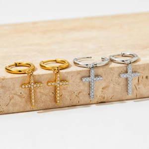 Vue détaillée des boucles d'oreilles croix dorées et argentées avec pierres scintillantes