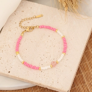 Macro detail of handmade beaded heart bracelet with pink and white beads and gold lobster clasp