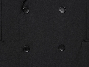 Detail view of premium black woven fabric and four-button closure on a loose vest