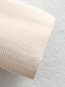 Macro view showing the premium beige cotton twill fabric texture of the blazer
