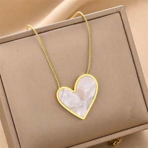 Detailed close-up of golden heart pendant with white marble inlay on jewelry box