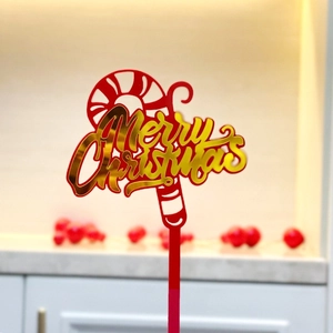 Detail of red and gold Merry Christmas cake topper with candy cane and festive lettering