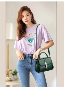 Detailed view of the green soft leather crossbody bag carried by a model outdoors