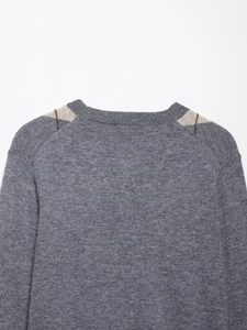 Detail showing grey argyle wool sweater collar and shoulder with knit texture