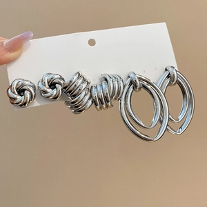 Detailed close-up of a silver earring set with knot and hoop designs on a card