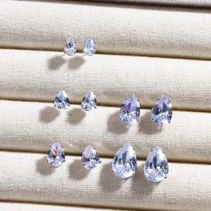 Macro view of four pairs of teardrop-shaped zircon earrings on a velvet display tray
