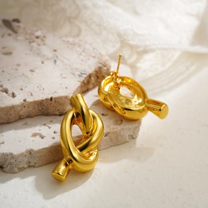 Detailed view of 18K gold knot earrings featuring a polished mirror finish on stone surface