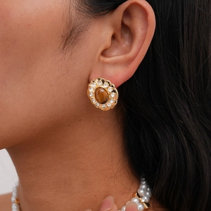 Close-up of vintage gold earrings with tiger eye stone and crystal inlay for women