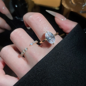Macro shot of oval-cut zircon gold ring set with sparkling stones on woman finger