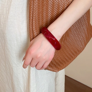 Detail of dark red acrylic bangle with amber texture worn with a stylish outfit