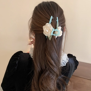 Detail of orchid hair claw clip with white flowers and green leaves on blue base