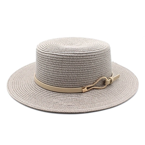 Close-up of woven straw hat featuring a leather band and geometric gold buckle detail