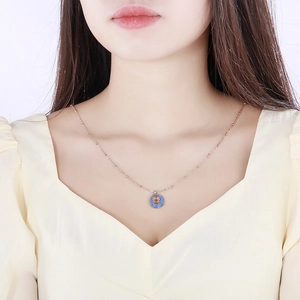 Close-up of rose gold Cancer zodiac pendant necklace with blue enamel on female neck