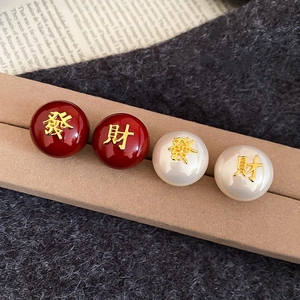 Gros plan de boucles d'oreilles rouge et blanc nacré avec caractères chinois dorés polis