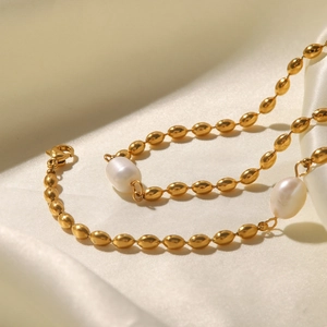 Elegant gold bean chain with baroque freshwater pearls on white silk background