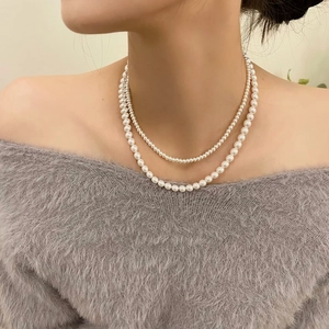 Double-layered 2mm white crystal pearl necklace styled on a soft knit sweater