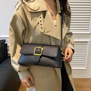 Detail of a black leather crossbody bag with elegant gold D-ring hardware on a model