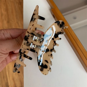 Detailed view of leopard print hair claw clip with unique butterfly wing wavy edge design