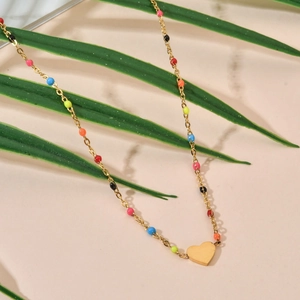 Détail du collier en chaîne dorée avec perles colorées et pendentif cœur doré