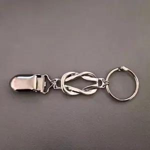 Détail macro du clip foulard vintage argenté avec nœud infini sur fond de cuir texturé