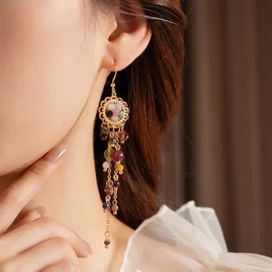 Vintage gold tassel earrings with colorful beads and floral hollow base on a female model