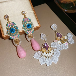 Detailed shot of vintage resin drop earrings with crystal accents on beige leather