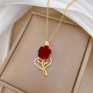 Detail of heart pendant with red flocked rose and crystals on a gold steel necklace