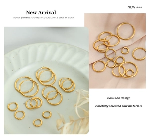 Detailed view of various sizes gold hoop earrings on ceramic plate and pink silk background