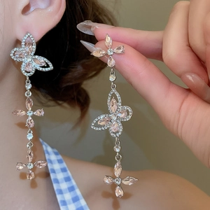 Detail shot of long tassel butterfly earrings with pink crystals on model