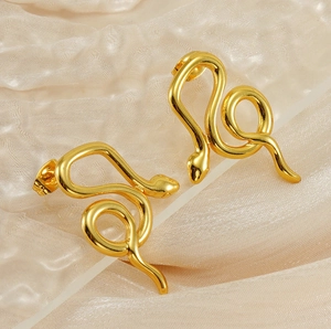 Macro shot of 18K gold plated snake stud earrings on elegant champagne silk fabric