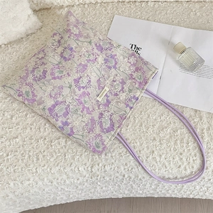 Detail of lavender lace tote bag with white floral embroidery on a soft white rug
