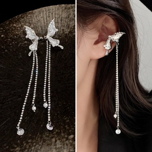 Détail de boucles d'oreilles nœud argentées avec pompons strass et perles sur modèle