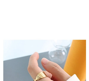 Macro view of wide gold-plated multi-layer wavy ring worn on thumb showing texture