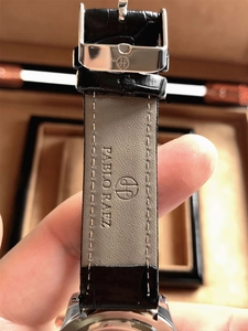 Macro shot of black leather watch strap with silver buckle and embossed logo detail