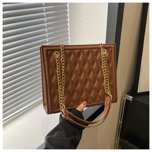 Detail of a brown quilted leather chain bag showing fine texture and gold hardware