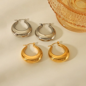 Polished hollow 18K gold and silver stainless steel hoop earrings on a beige background