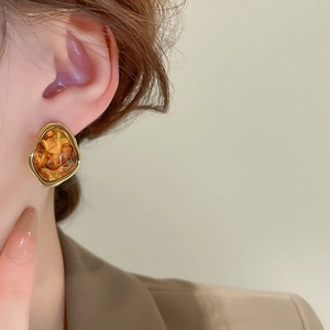 Close-up of irregular amber resin geometric earrings with gold-plated metallic frame