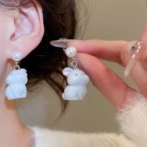 Close-up of model wearing white flocked rabbit earrings with elegant pearl studs