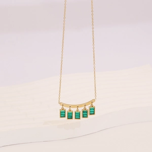 Gold geometric necklace featuring a curved bar with five green square glass pendants