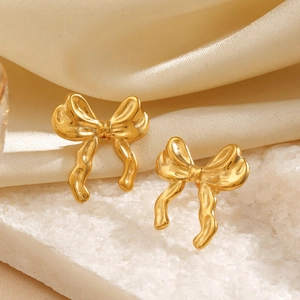 Elegant 18K gold-plated ribbon bow earrings displayed on a white textured mineral stone