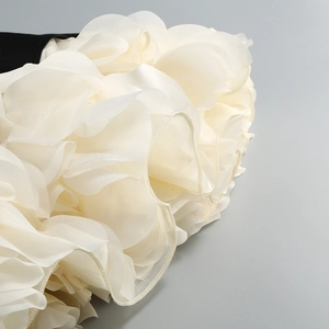 Close-up of layered cream ruffles and black stitching on a square neck party gown