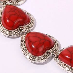 Macro detail of vintage bohemian bracelet with red heart turquoise charms and silver relief