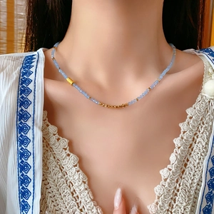 Vue détaillée du collier en perles bleues avec touches dorées sur le cou du mannequin