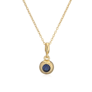 Detail of gold circular pendant necklace featuring a brilliant blue round zircon gemstone