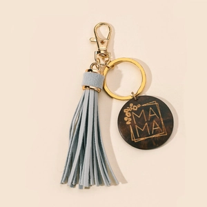 Detail of blue tassel keychain with gold metal clasp and engraved MAMA wood tag